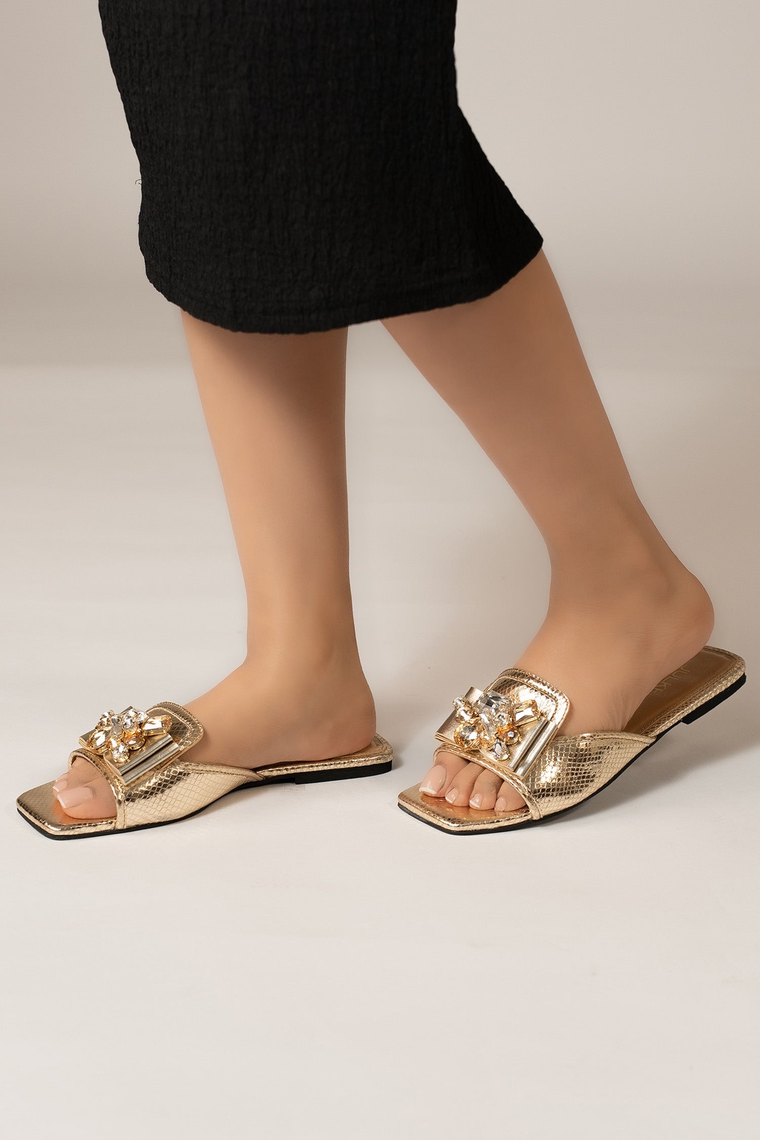 Womens flat slides in gold colour with shiny foilded reptile texture and golden asymmetric rhinestone brooch by JULKE.