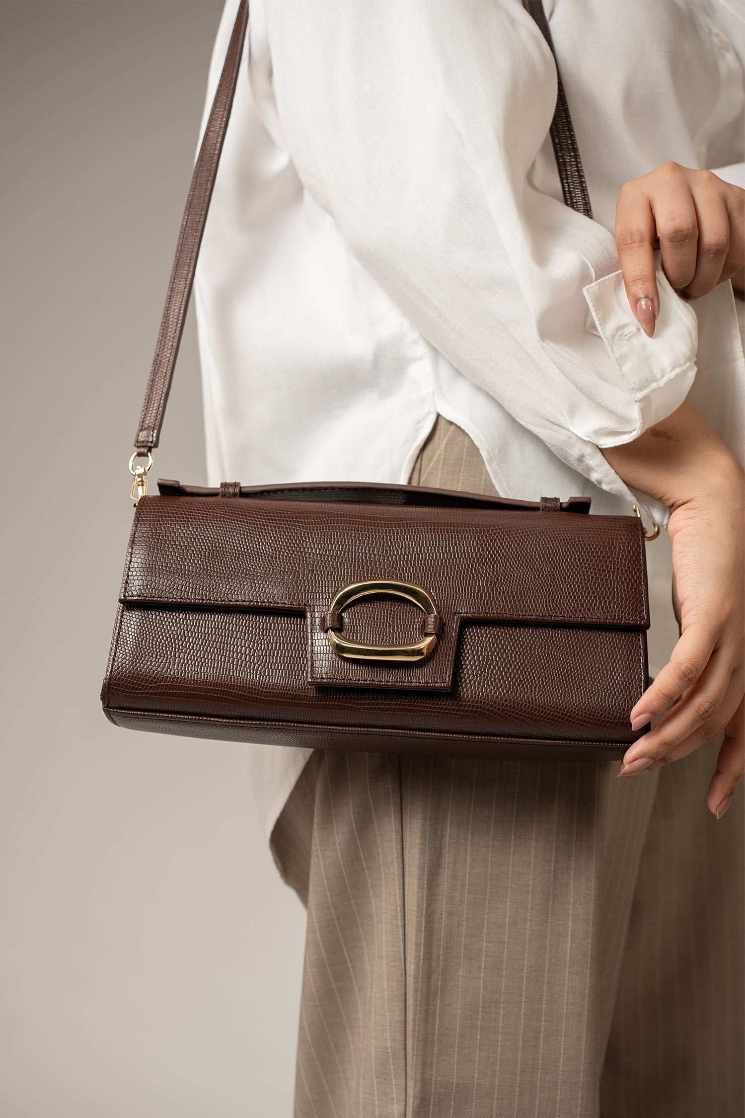 Womens leather top handle shoulder bag in dark brown colour with reptile texture and oval gold buckle by JULKE.