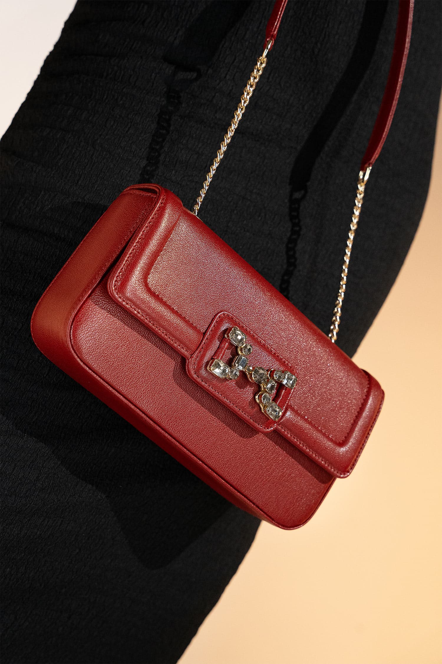 Women's leather shoulder bag in maroon colour in rectangular shape with gold horse-bit buckle of transparent circle rhinestones and short chain and leather shoulder strap by JULKE