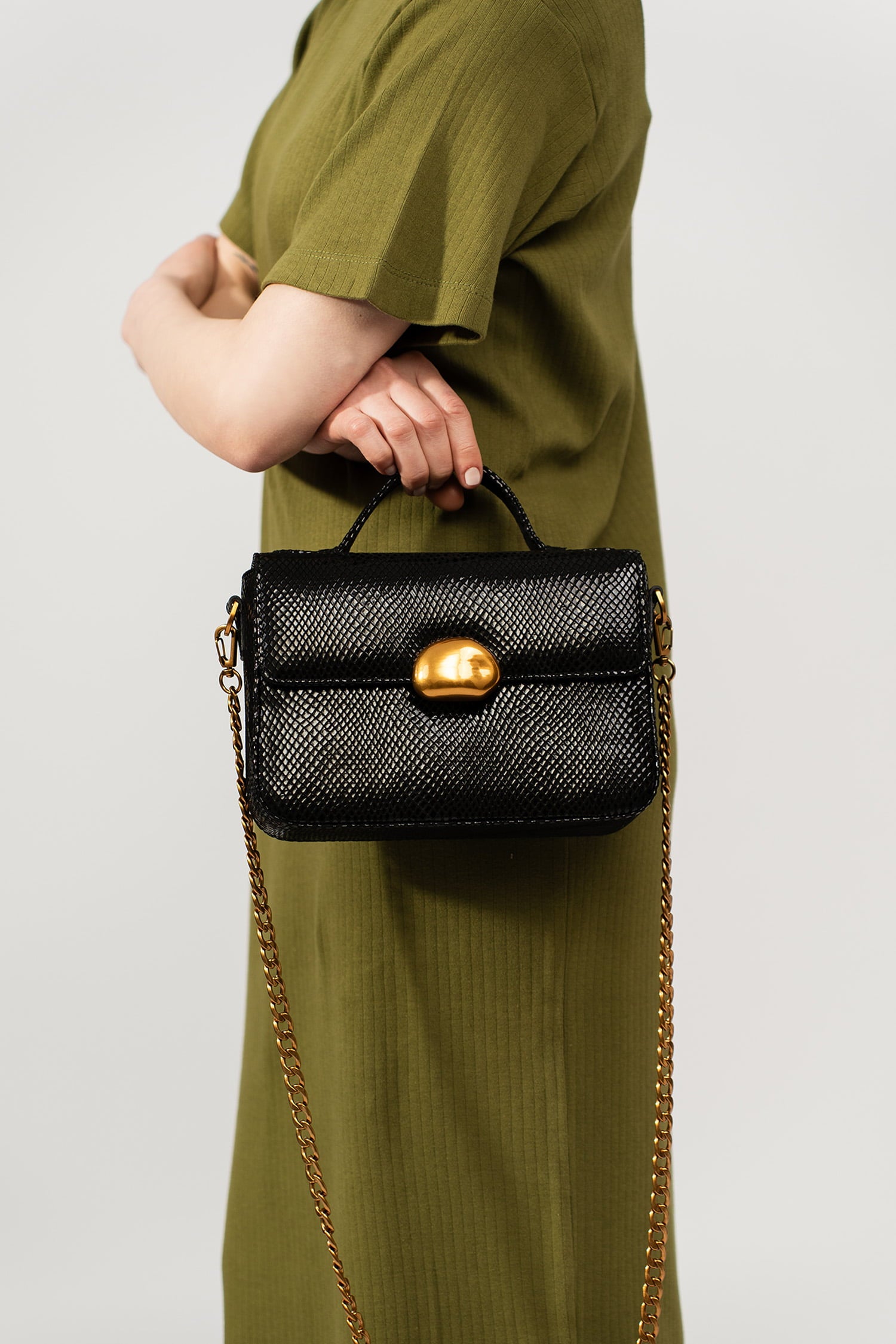 Womens leather top handle shoulder bag in glossy black reptile texture with unique golden metallic lock and metallic chain strap by JULKE.