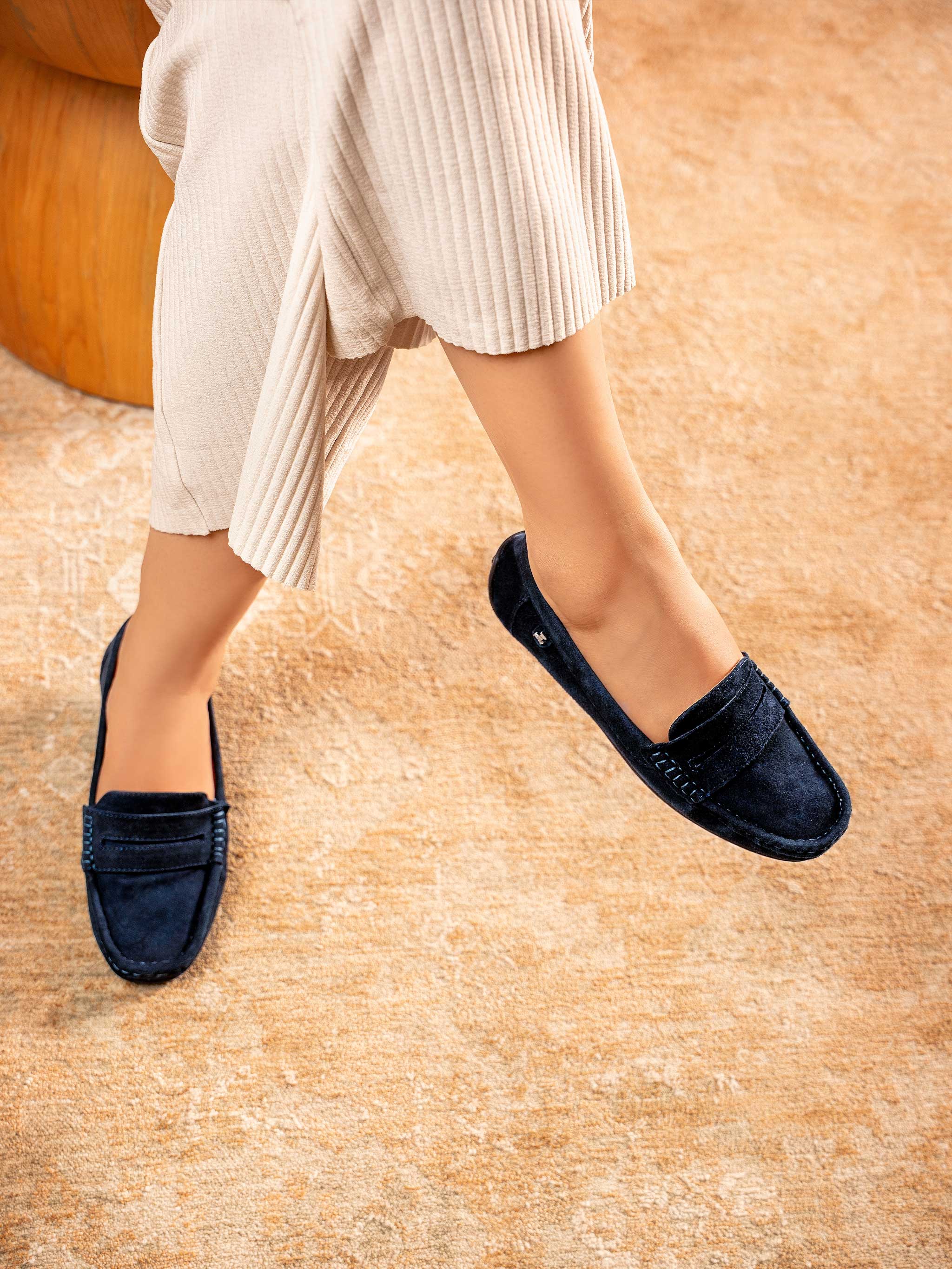 Tabby women’s winter moccasins in royal blue suede leather by JULKE, featuring a soft slip-on design perfect for comfort and everyday wear, styled with beige pleated trousers on a cozy indoor carpet.