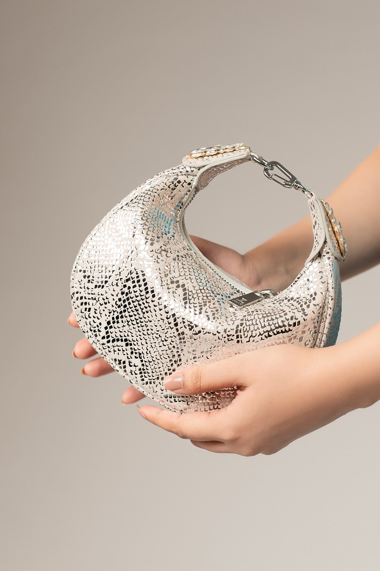 Women's leather mini halfmoon bag in silver colour with 3d reptile texture and unique clip-on handle by JULKE.