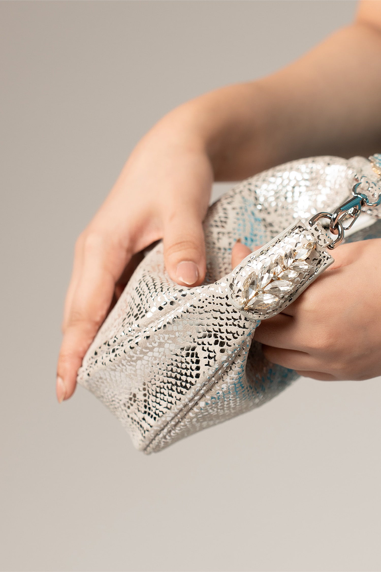Women's leather mini halfmoon bag in silver colour with 3d reptile texture and unique clip-on handle by JULKE.