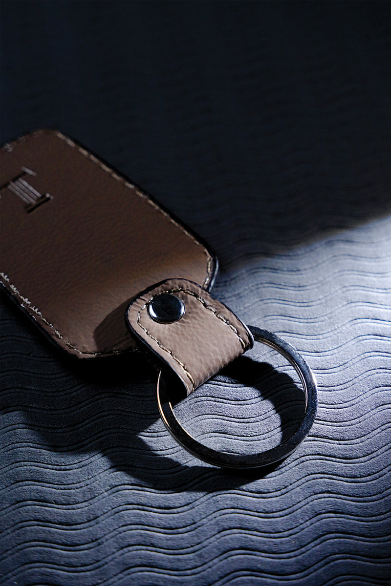 Leather key chain in grey brown colour with weaving and metal ring by JULKE