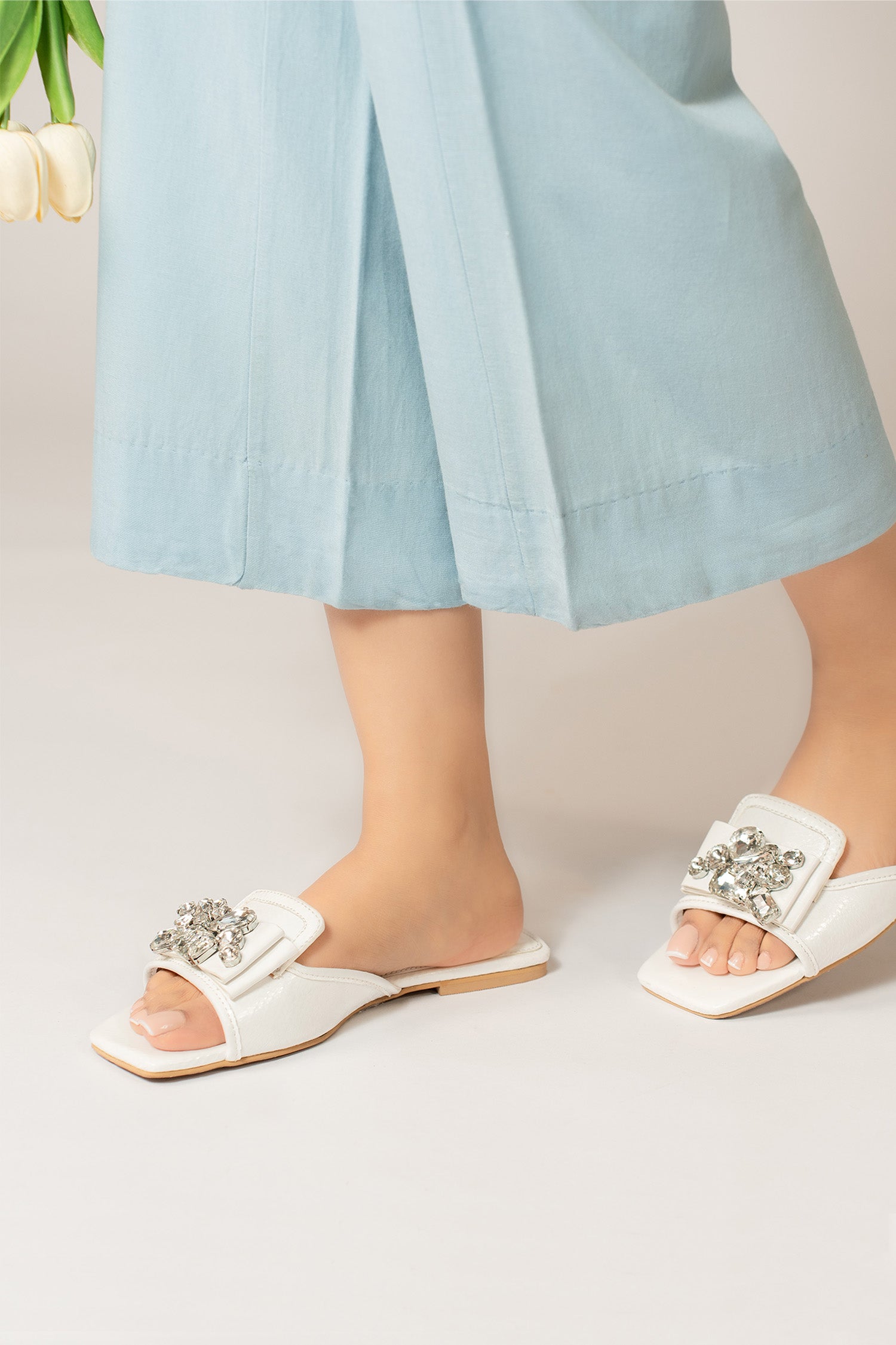 Womens flat slides in white colour with glossy reptile texture and asymmetric rhinestone brooch by JULKE.