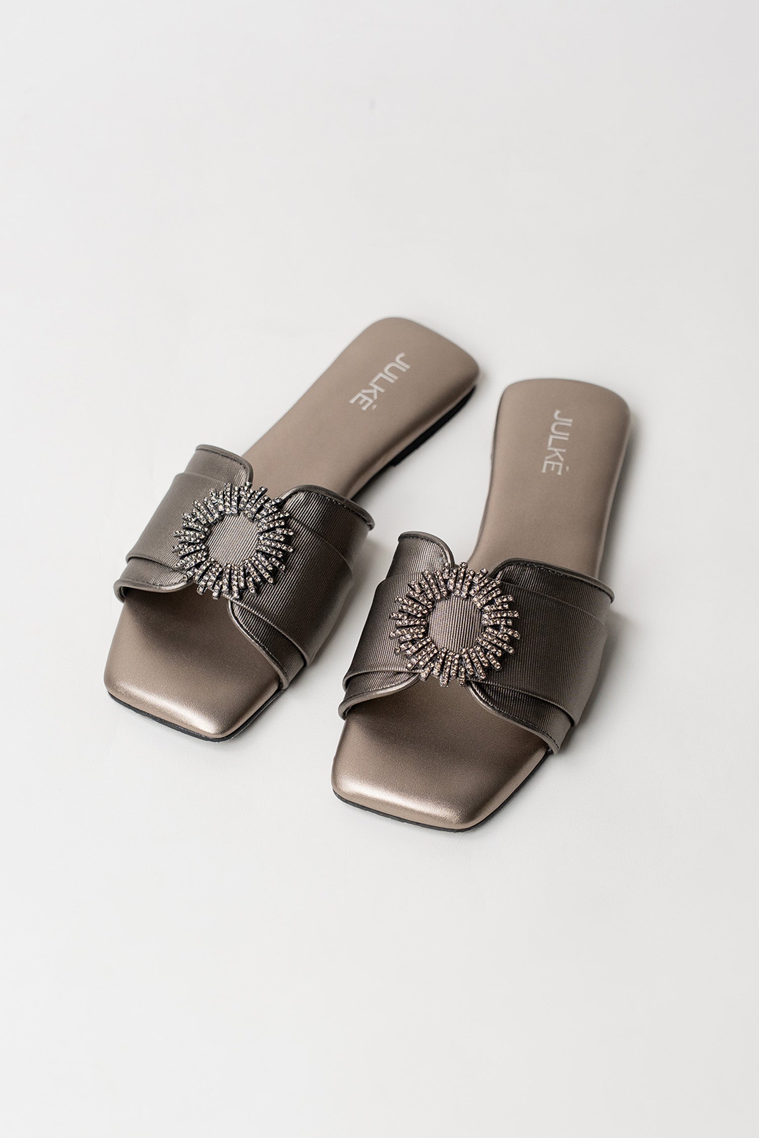 Women's festive leatherite flat shoes in gun metal colour with round silver diamante brooch and padded insock by JULKE. 