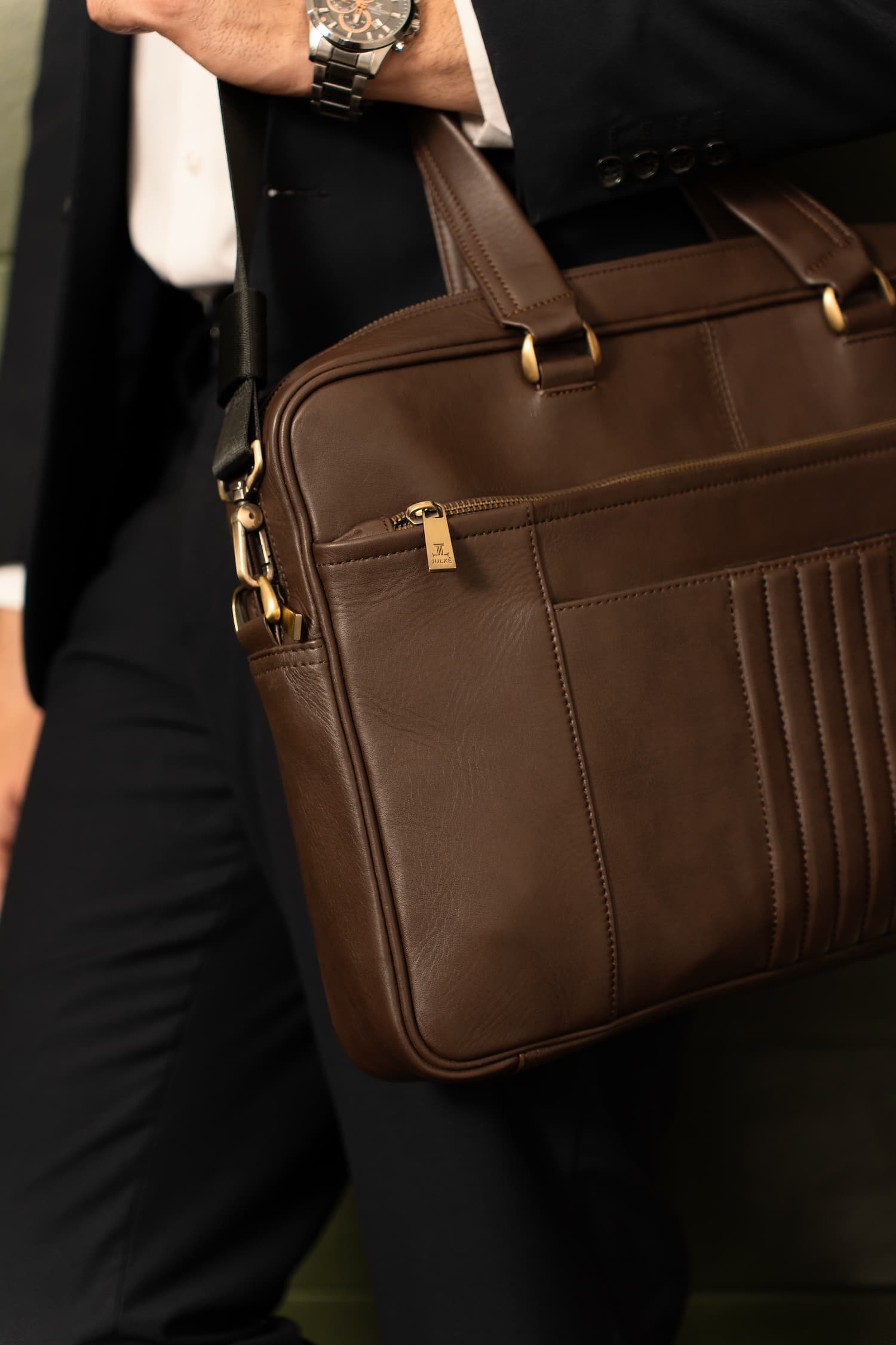 Mens full grain leather laptop bag in dark brown colour with etxra compartments and metallic gold hardware by JULKE. 