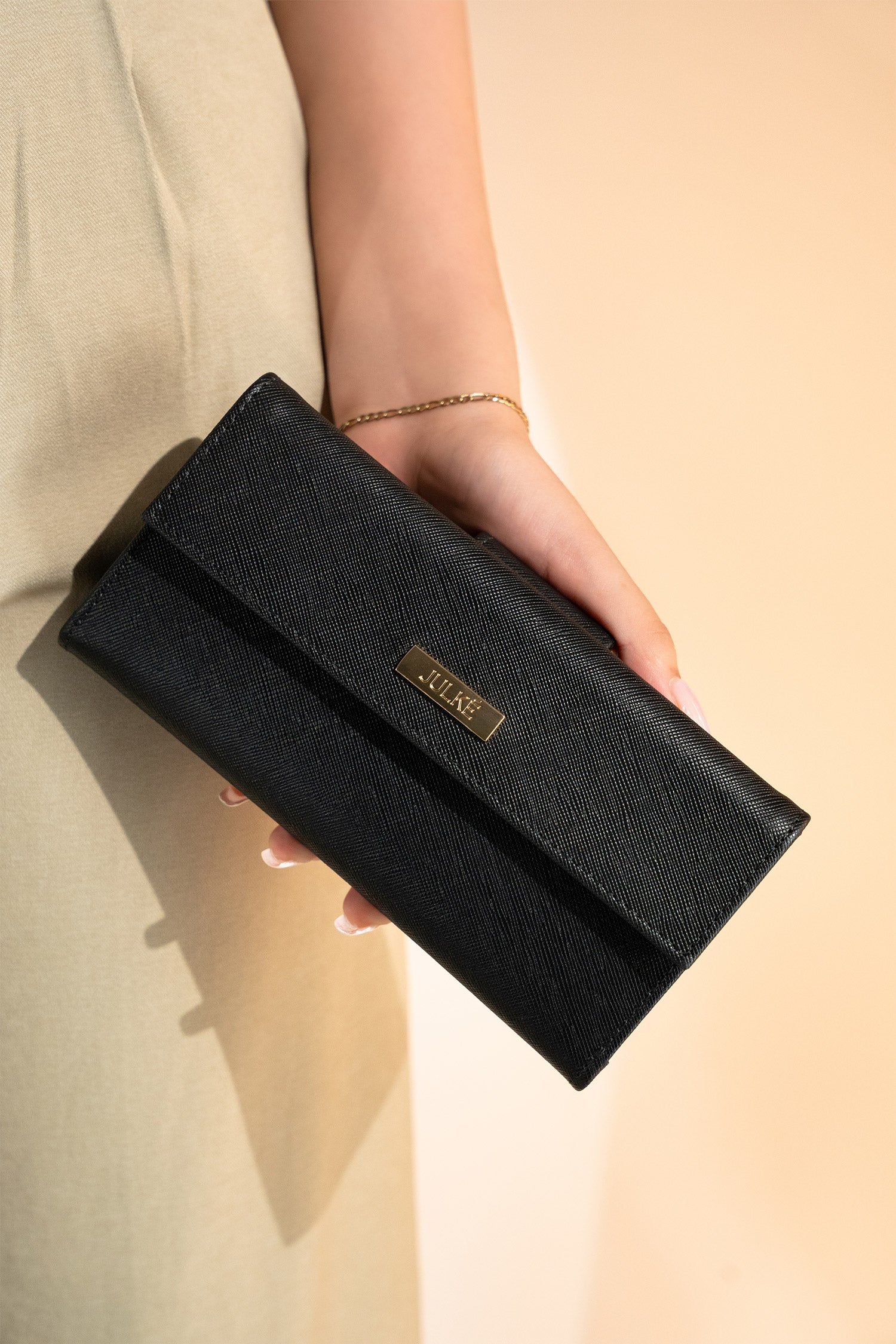 Women's leather long wallet in black colour in crosshatch texture with gold metal press button strap and extra pockets by JULKE. 