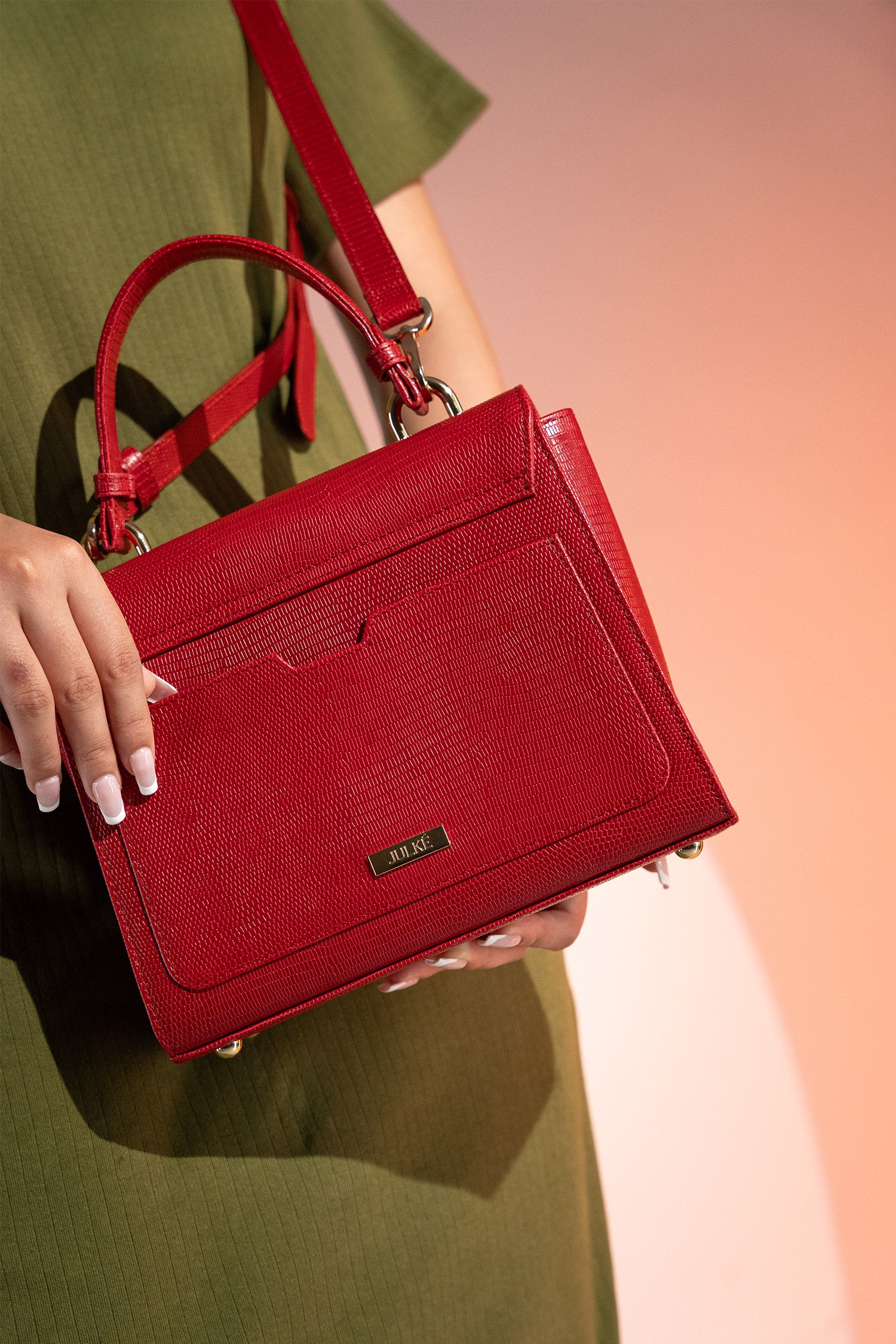 Women's reptile texture leather top handle bag in red colour with detachable shoulder strap and unique oval twist lock by JULKE. 