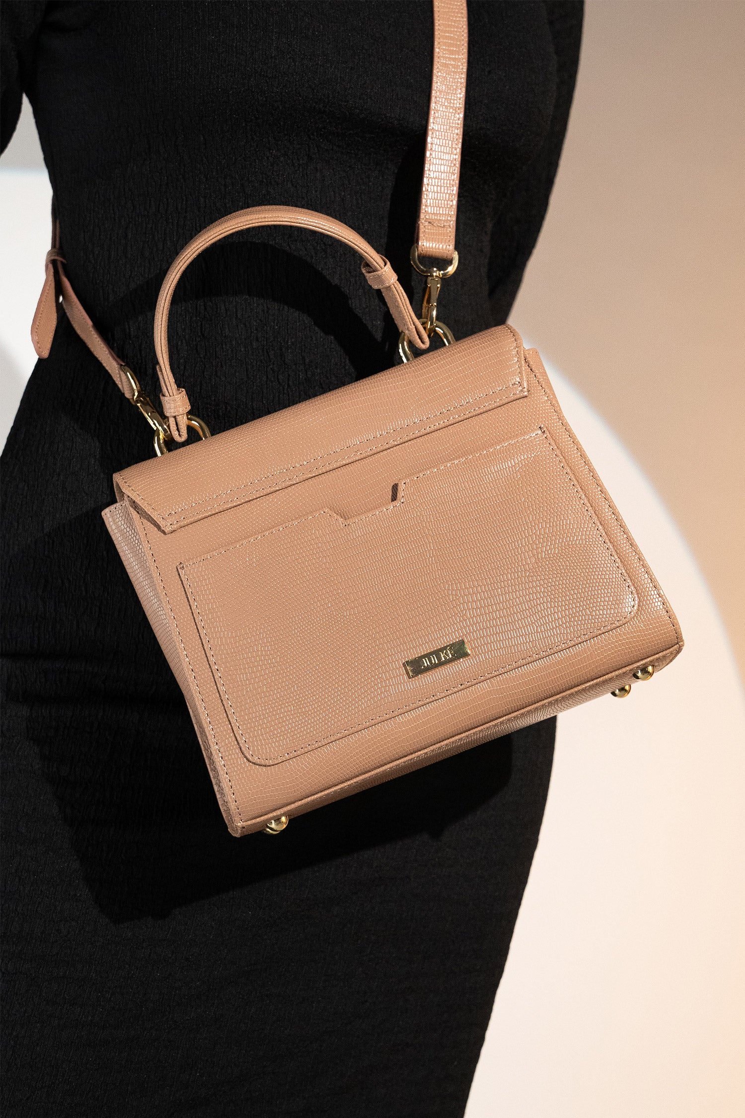 Women's reptile texture leather top handle bag in beige colour with detachable shoulder strap and unique oval twist lock by JULKE. 