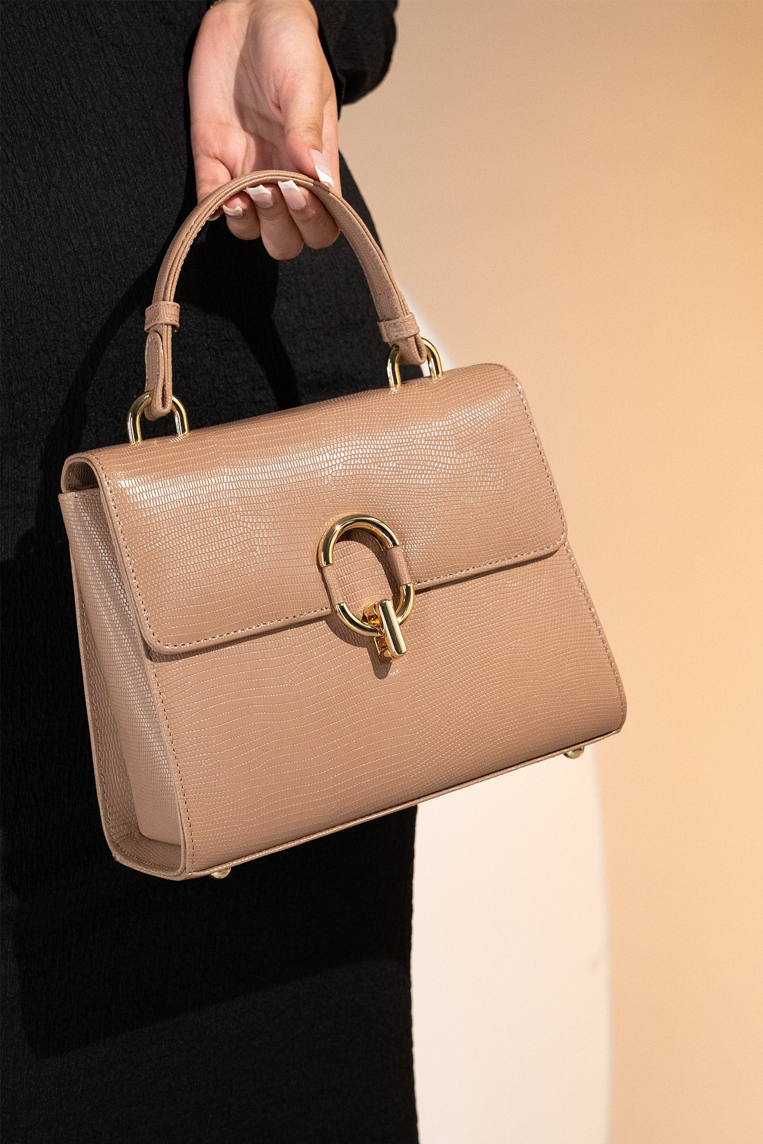 Women's reptile texture leather top handle bag in beige colour with detachable shoulder strap and unique oval twist lock by JULKE. 