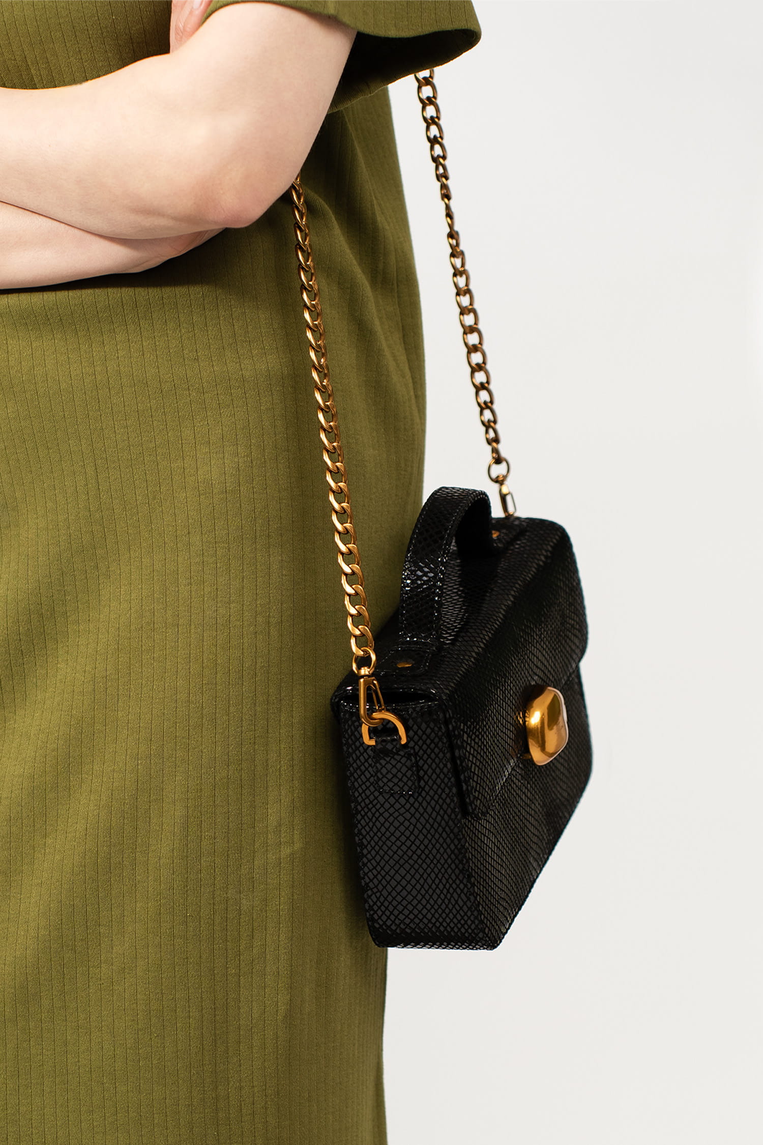 Womens leather top handle shoulder bag in glossy black reptile texture with unique golden metallic lock and metallic chain strap by JULKE. 