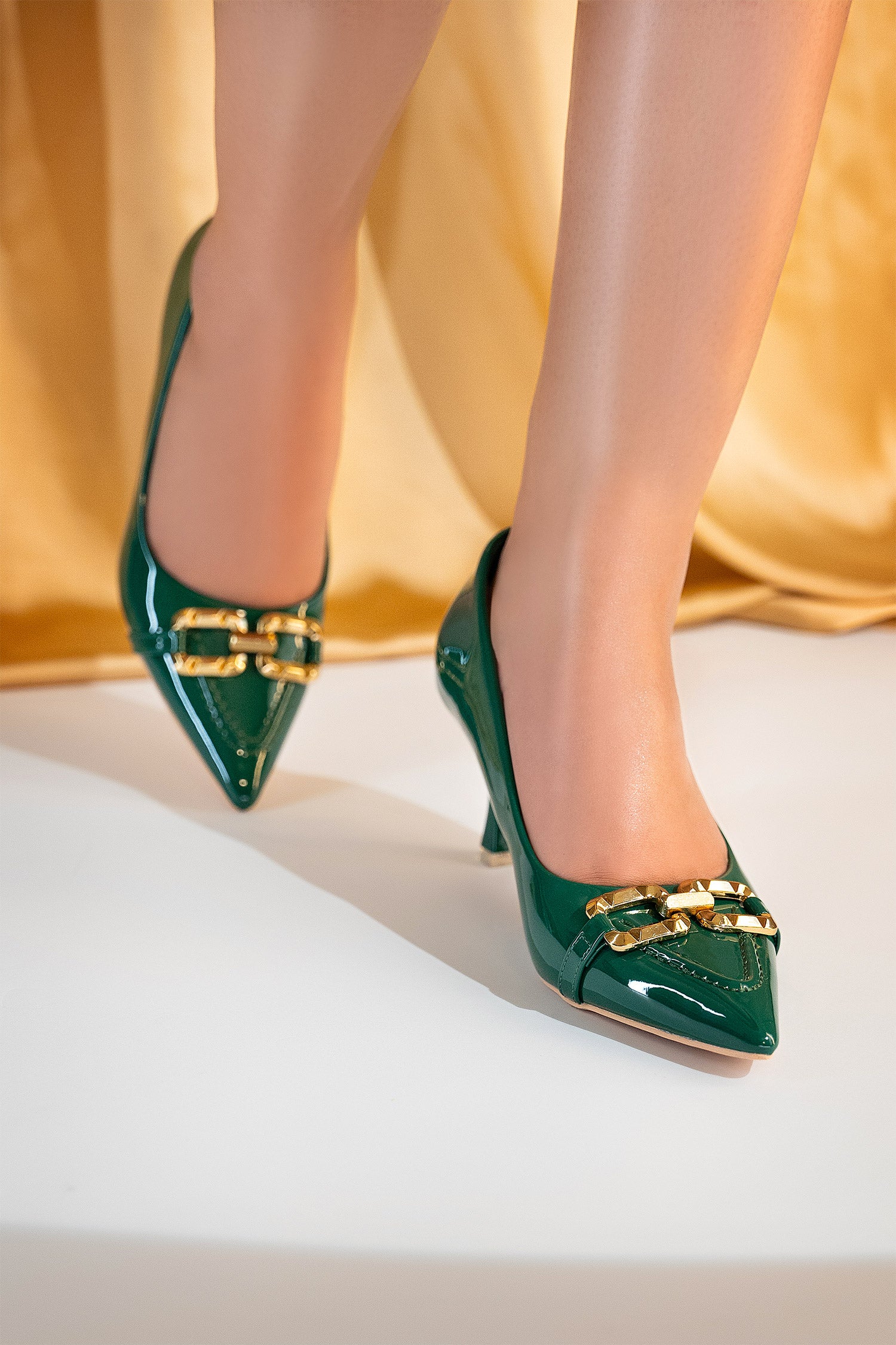 Women's heel pumps in dark green colour with pointed toe and spiky golden horse-bit buckle by JULKE 