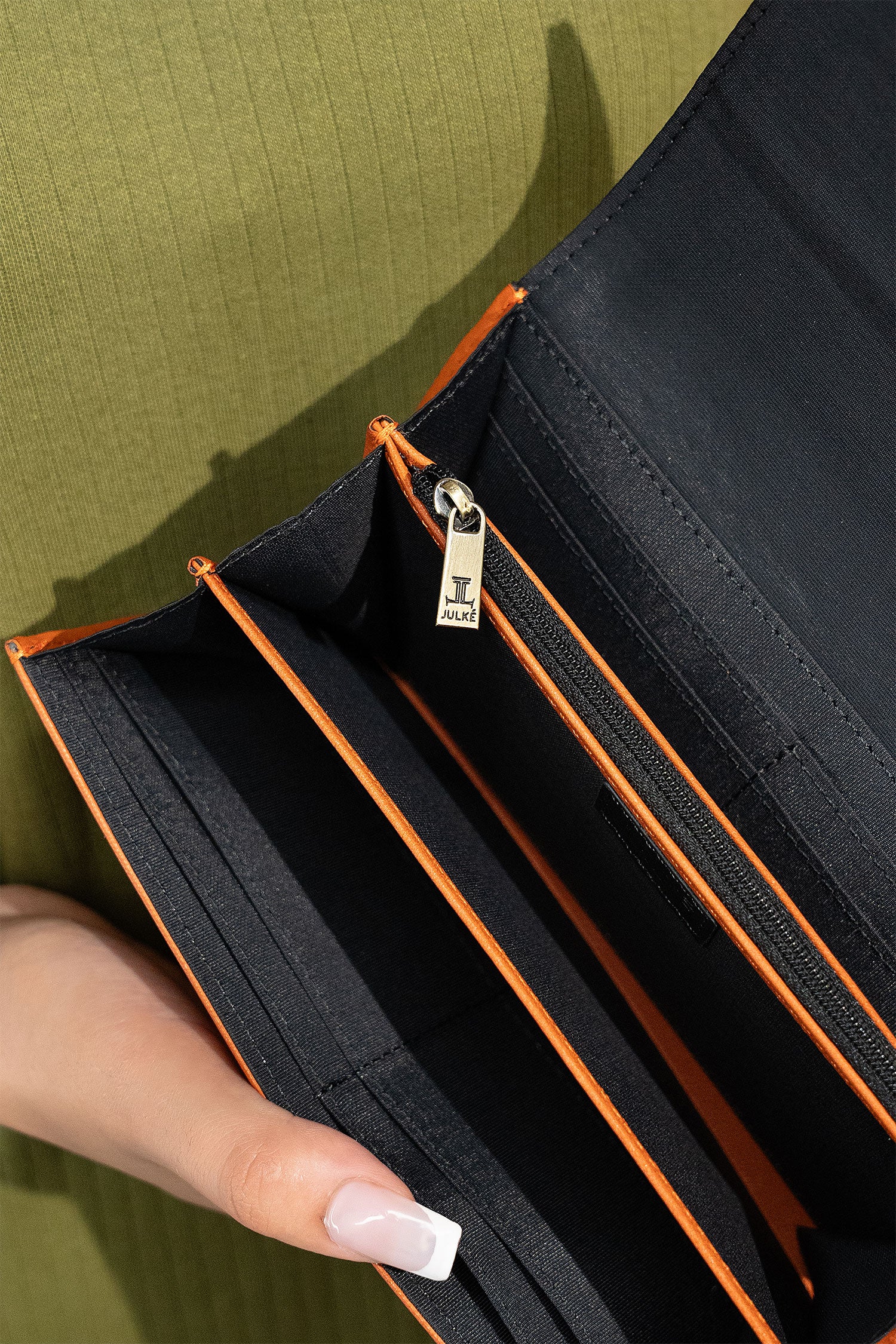 Women's leather long wallet in dark orange colour in envelope shape with long pockets and metallic horse-bit buckle and brand logo by JULKE. 