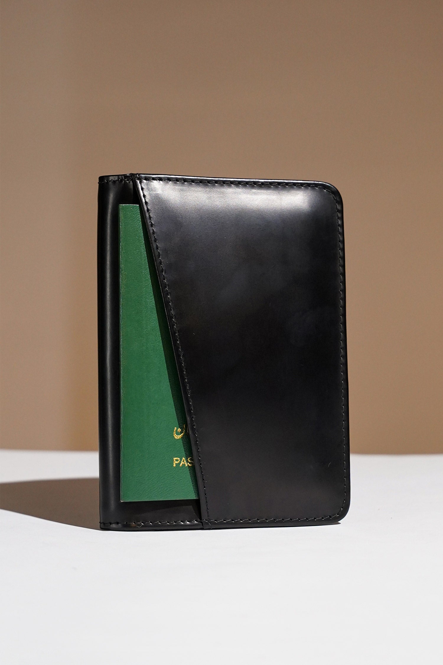 Mens leather bifold passport wallet in black colour with white contrast stitching and metal brand logo by JULKE