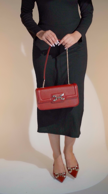 Women's sling back pointed toe heels in dark red colour and matching leather shoulder bag with glossy dragon scale texture and rhinestone horse-bit buckle by JULKE. 